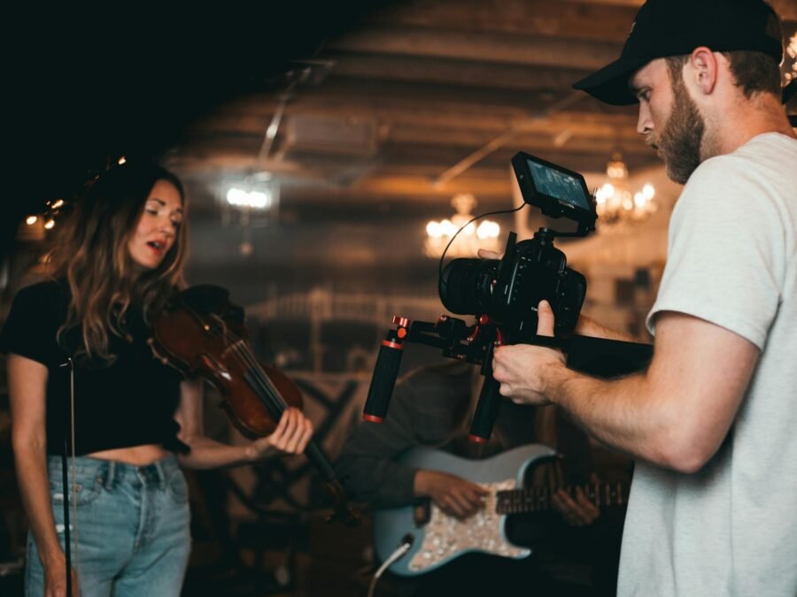 Man Taking a Video of a Woman Carrying a Violin