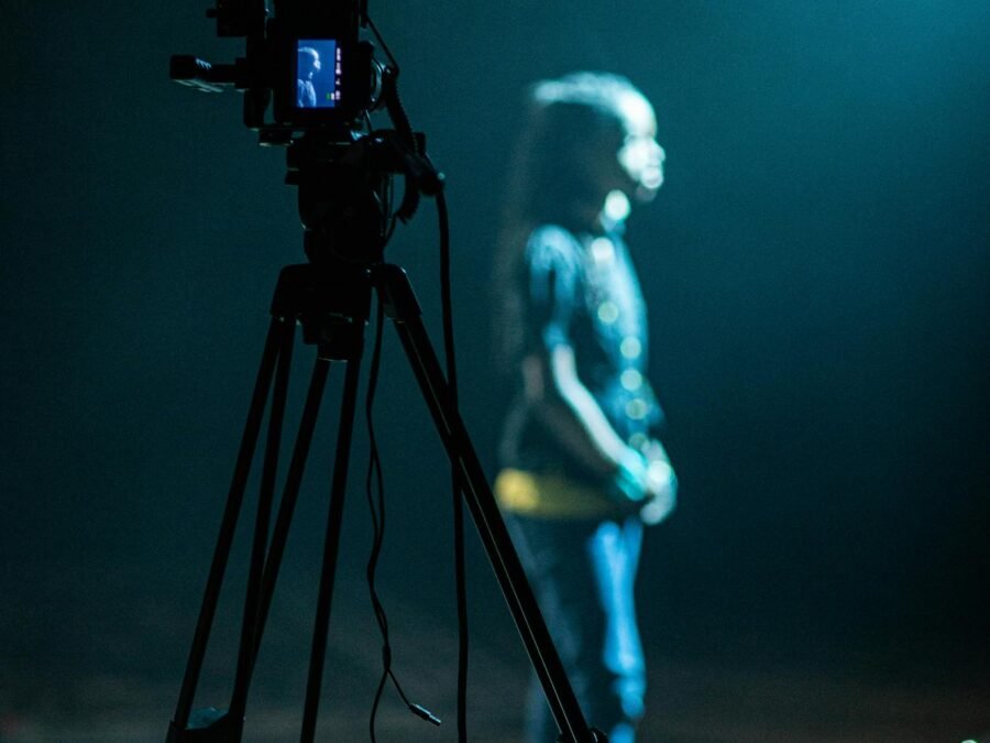 Side view of unrecognizable girl on stage near contemporary camera filming video during rehearsal